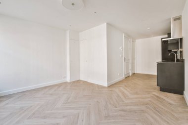 Pencereleri ve ahşap parke zemini olan boş beyaz mutfağın içi.