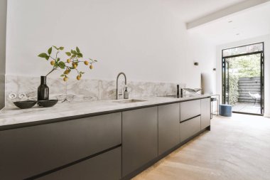 Günümüz minimalist tasarımı. Hafif stüdyo dairesinin ahşap masası ve oturma odası ile beyaz duvarları ve parke zemini arasında yemek masası ve sandalyeleri var.