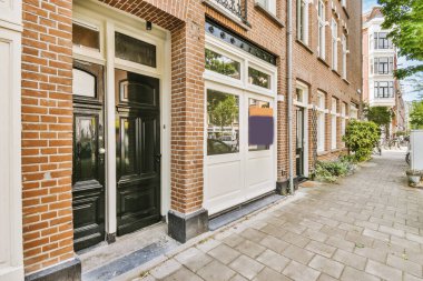 Levhalı, kaldırımlı ve ahşap kapılı bir binanın ön manzarası daireye çıkıyor.