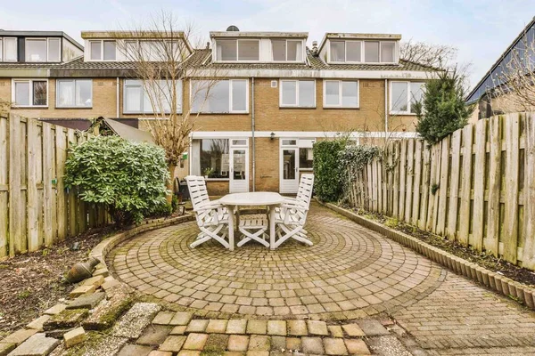 Neat paved patio with sitting area and small garden near wooden fence