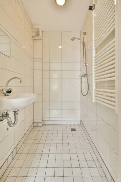 近代的な洗面所のシャワーキャビン近くの白いタイル張りの壁に取り付けられた長方形の鏡ときれいなシンク付きのモダンなバスルームのインテリア — ストック写真