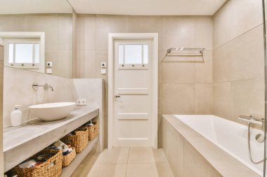 Aynalı lavabo ve temiz küvet modern banyoda cam kapılı ve beyaz fayanslı duvarları olan duş kutusunun yanında.