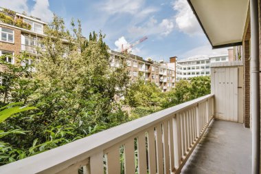 Dar tuğlalı balkon, metal parmaklıklar ve kapı.