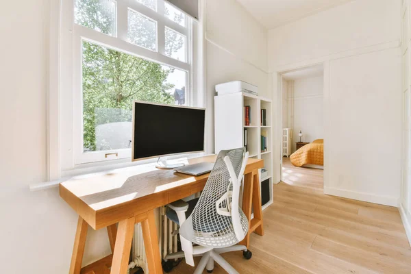 現代のアパートの光の職場でコンピュータモニターとホワイトボードと机の近くに配置快適な椅子 — ストック写真