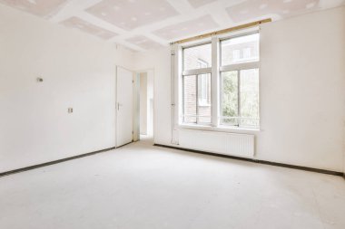 Evdeki boş ışık odasında, beyaz duvardaki plastik pencere ve radyatör.