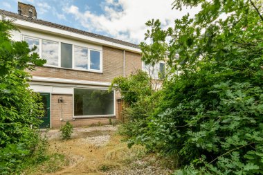 Oturma alanı ve ahşap çitlerin yanındaki küçük bahçesi olan düzgün asfaltlı bir avlu.