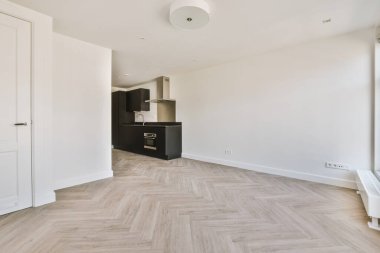 Pencereleri ve ahşap parke zemini olan boş beyaz mutfağın içi.