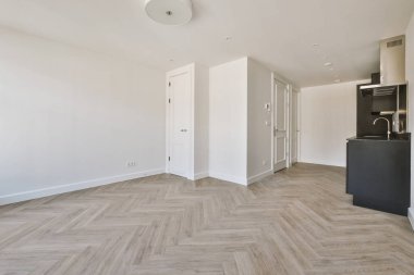 Pencereleri ve ahşap parke zemini olan boş beyaz mutfağın içi.