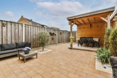 Neat paved patio with sitting area and small garden near wooden fence