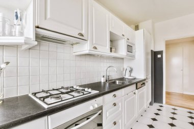 Geniş pencereli hafif küçük ev mutfağı modern kentsel dairede dolaplar ve raflarla donatılmış.