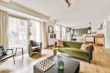 Günümüz minimalist tasarımı. Hafif stüdyo dairesinin ahşap masası ve oturma odası ile beyaz duvarları ve parke zemini arasında yemek masası ve sandalyeleri var.
