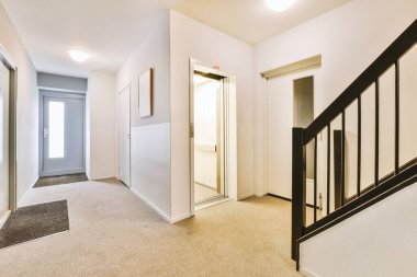 Minimalist iç tasarımı olan modern lüks dairenin ikinci katına çıkan ahşap merdivenli beyaz koridor.