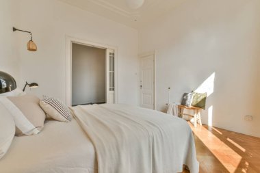 Comfortable bed with pillows and warm blanket located near window in stylish bedroom with green walls