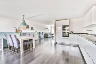 Günümüz minimalist tasarımı. Hafif stüdyo dairesinin ahşap masası ve oturma odası ile beyaz duvarları ve parke zemini arasında yemek masası ve sandalyeleri var.