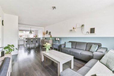 Günümüz minimalist tasarımı. Hafif stüdyo dairesinin ahşap masası ve oturma odası ile beyaz duvarları ve parke zemini arasında yemek masası ve sandalyeleri var.