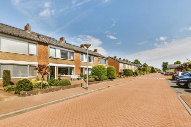 Arabaları, ağaçları ve fenerleri olan boş bir kaldırımdan panorama manzaralı evler.