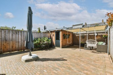 Oturma alanı ve ahşap çitlerin yanındaki küçük bahçesi olan düzgün asfaltlı bir avlu.