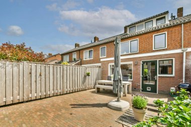 Oturma alanı ve ahşap çitlerin yanındaki küçük bahçesi olan düzgün asfaltlı bir avlu.