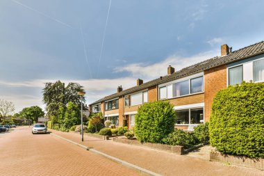 Arabaları, ağaçları ve fenerleri olan boş bir kaldırımdan panorama manzaralı evler.