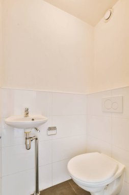 Lavabolu ve duvarlı, beyaz duvarlı ve kareli tuvaletli dar bir tuvalet.