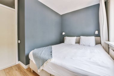 Yatak odasının iç tasarımı, yatak odası ve ahşap gardırop modern dairenin penceresinin kenarına yerleştirilmiş.