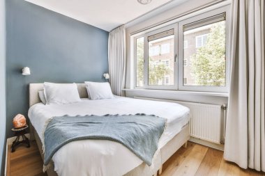 Yatak odasının iç tasarımı, yatak odası ve ahşap gardırop modern dairenin penceresinin kenarına yerleştirilmiş.