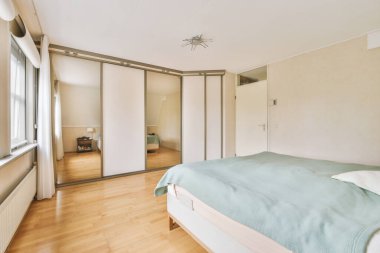 Modern minimalist tarzda pencereli mansard yatak odasındaki yeşil duvarın yanına konforlu yatak