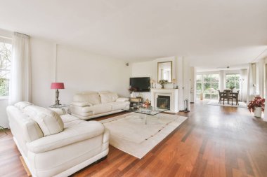 Lüks bir ev tasarımı. Yanan şömineli rahat bir oturma odası. Gün ışığında rahat bir kanepe ve halı.