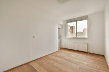 Evdeki boş ışık odasında, beyaz duvardaki plastik pencere ve radyatör.