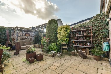 Oturma alanı ve ahşap çitlerin yanındaki küçük bahçesi olan düzgün asfaltlı bir avlu.