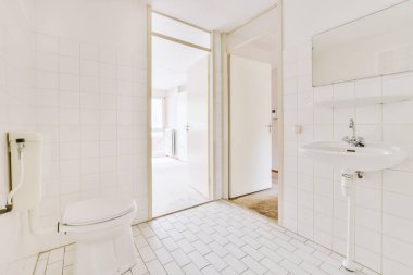 Modern sifon tuvaleti ve seramik lavabo aynanın yanındaki beyaz fayanslı duvarlara ve evdeki küçük tuvaletteki havluya monte edildi.