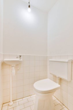Modern sifon tuvaleti ve seramik lavabo aynanın yanındaki beyaz fayanslı duvarlara ve evdeki küçük tuvaletteki havluya monte edildi.