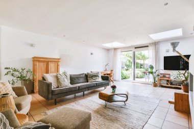 Çağdaş dairenin pencerelerine karşı rahat kanepesi ve televizyonu olan oturma odası.