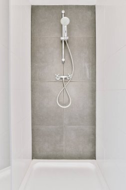 Duş muslukları cam bölmenin yanındaki fayanslı duvara bağlı ve evdeki tuvaletteki süs pervazı.