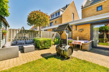 Oturma alanı ve ahşap çitlerin yanındaki küçük bahçesi olan düzgün asfaltlı bir avlu.