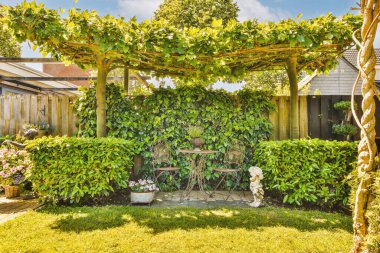 Neat paved patio with sitting area and small garden near wooden fence