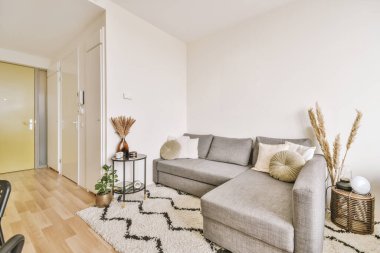 Çağdaş dairenin geniş odasındaki dinlenme odası ve mutfağın yakınındaki sandalyeli ve çiçekli masa.