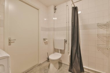 Duvara asılmış tuvalet ve köşedeki bej fayanslı lavabo.