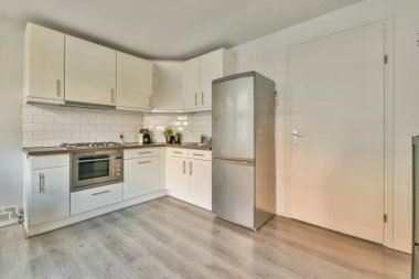 Çağdaş dairenin geniş odasındaki dinlenme odası ve mutfağın yakınındaki sandalyeli ve çiçekli masa.