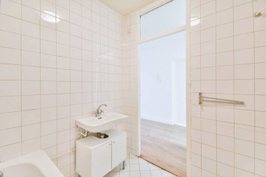 Aynalı lavabolar ve modern banyoda beyaz fayanslı duvarları olan temiz bir küvet.