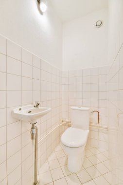 Lavabolu ve duvarlı, beyaz duvarlı ve kareli tuvaletli dar bir tuvalet.