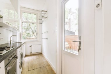 İyi organize edilmiş küçük bir ev mutfağı pencerenin altında lavabo, sobalı hafif mobilyalar ve kentsel apartmanda buzdolabı var.