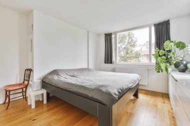 Yatak odasının iç tasarımı, yatak odası ve ahşap gardırop modern dairenin penceresinin kenarına yerleştirilmiş.