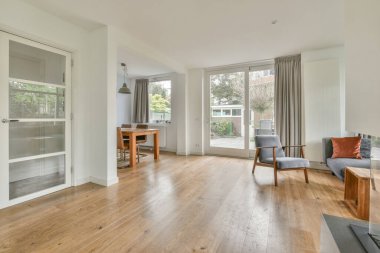 Modern apartmandaki dekorasyonlu ve televizyonlu, rahat koltuğun yanına yerleştirilmiş eski püskü ahşap masa.