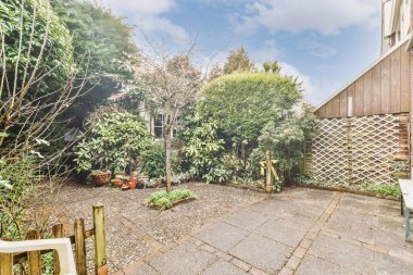 Ahşap çitlerin yanında küçük bahçesi olan basit geniş bir teras.