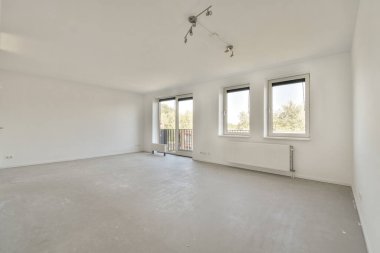 Pencereleri ve ahşap parke zemini olan boş beyaz mutfağın içi.