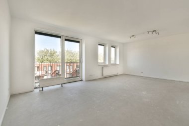 Pencereleri ve ahşap parke zemini olan boş beyaz mutfağın içi.