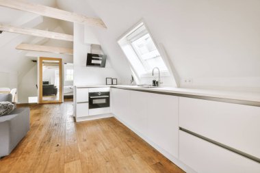 Günümüz minimalist tasarımı. Hafif stüdyo dairesinin ahşap masası ve oturma odası ile beyaz duvarları ve parke zemini arasında yemek masası ve sandalyeleri var.