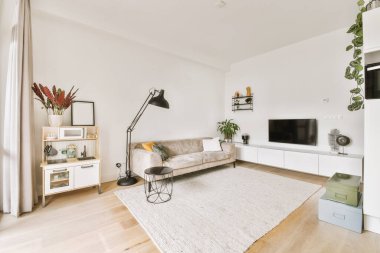 Mutfağın yakınındaki açık oturma odasında zarif avizenin altında yumuşak yastıklı büyük bir kanepe.