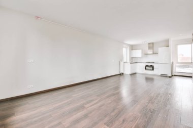 Pencereleri ve ahşap parke zemini olan boş beyaz mutfağın içi.